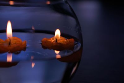 Close-up of burning tea lights in glass container