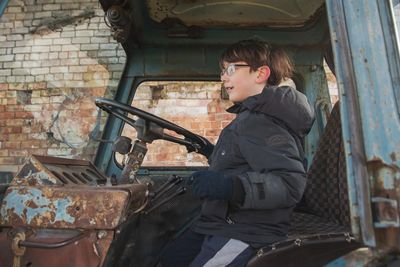 Side view of boy sitting in tractor