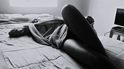 Low section of man relaxing on bed at home