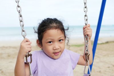 Portrait of smiling girl on swing at playground