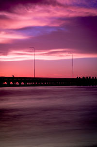 Bridge over sea against sky during sunset