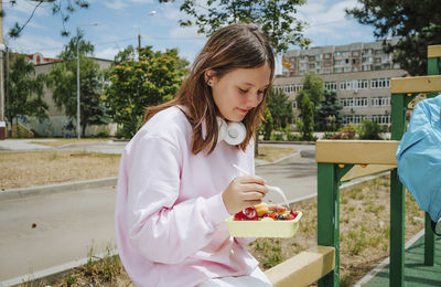 Girl eating food from lunch box on sunny day