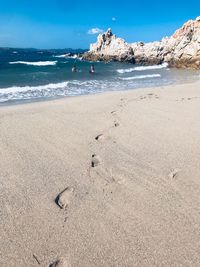 Footprints on sand at beach against sky