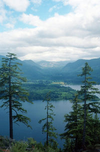 Scenic view of lake and mountains against cloudy sky