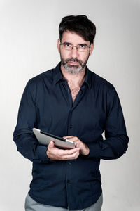 Portrait of serious mature man with digital tablet against white background
