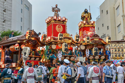 Large group of people in costumes standing on street in city