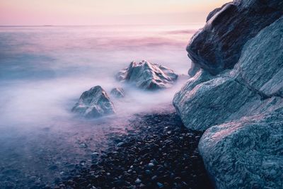 Scenic view of rock formation at sea against sky during sunset