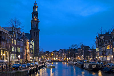 Boats in canal amidst buildings in city at dusk