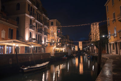 Canal amidst illuminated buildings in city at night