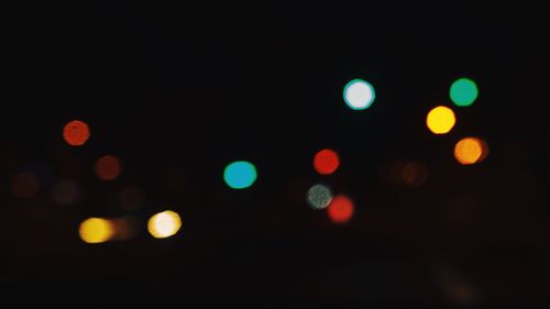 Defocused image of illuminated surrounded by colorful lights at night