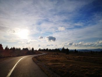 Road amidst field against sky