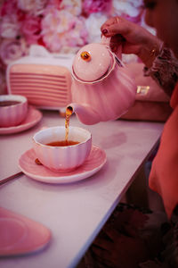 Person pouring tea cup on table