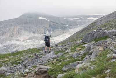 Rear view of backpacker walking on mountain