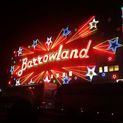 Low angle view of illuminated text against sky at night