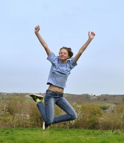 Teenage girl jumping against sky