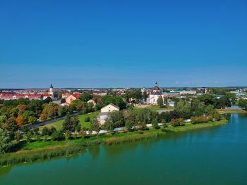 Scenic view of lake by buildings against clear blue sky