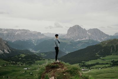 Woman standing on top of the rock overlooking the mountains