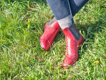 Young girl in red paddock boots with long tighs sitting in grass and waiting for horse and lesson.
