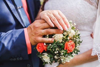 Midsection of wedding couple holding bouquet