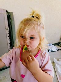 Cute baby girl holding flower at home