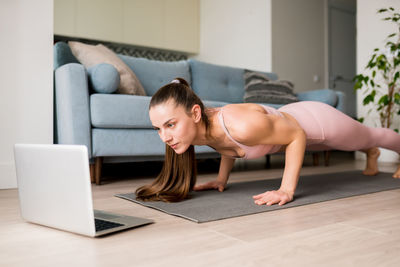 Plank workout to strong core. woman doing planking exercises online from laptop home. 