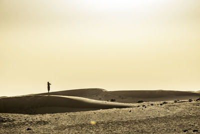 Silhouette man standing on desert against sky