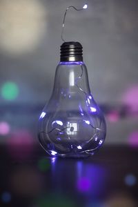 Close-up of illuminated light bulb on table