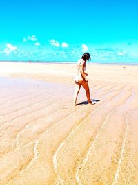 Full length of woman walking on sand at beach against sky