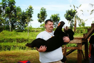 Male caretaker carrying black bear cub drinking from milk bottle