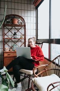 Young woman using laptop while sitting at balcony