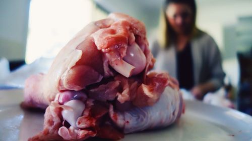 Close-up of meat in plate with person in kitchen