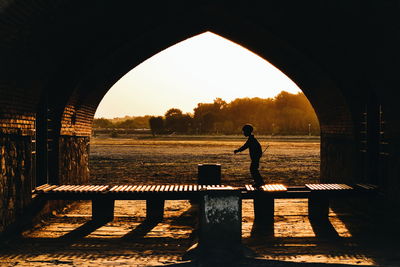 Silhouette man standing on field against sky during sunset