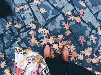 Low section of woman by dried leaves on wet footpath