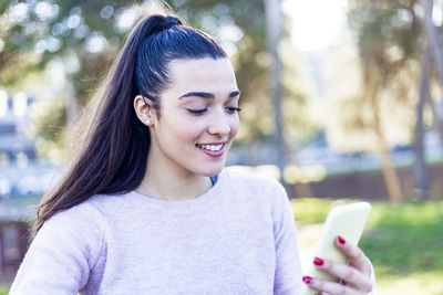 Young smiling woman using smart phone outdoors