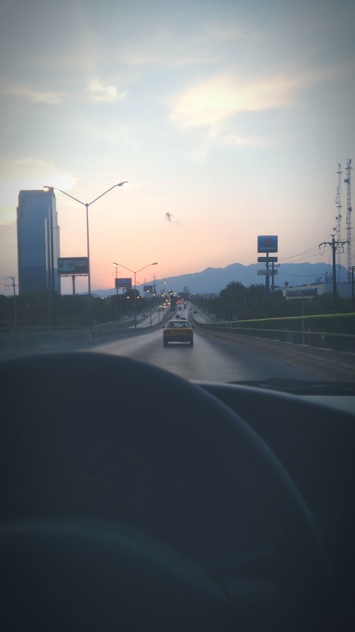 transportation, car, land vehicle, mode of transport, road, building exterior, architecture, sky, built structure, city, street, road marking, on the move, sunset, cloud - sky, street light, the way forward, travel, traffic, outdoors