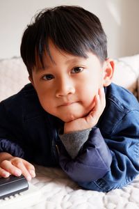 Portrait of cute boy lying on bed at home