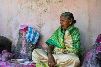 Full length of mature woman sitting against wall