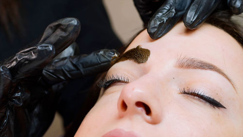 Cropped hands of beautician coloring woman eyebrow