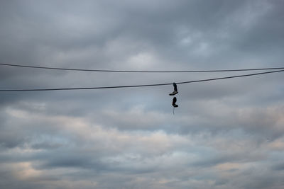 Low angle view of a bird flying against cloudy sky