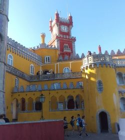 People walking in historic building against sky in city