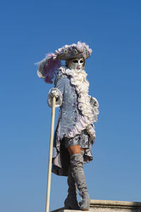 Low angle view of person standing against blue sky