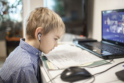 Side view of boy attending online lectures at home