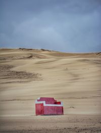 Red sofa on idyllic desert against sky