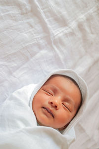 High angle view of baby sleeping on bed