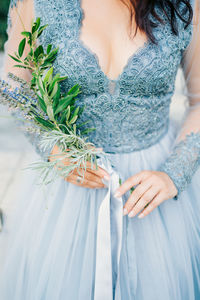 Midsection of woman holding umbrella standing by plant