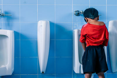 Rear view of man standing in bathroom