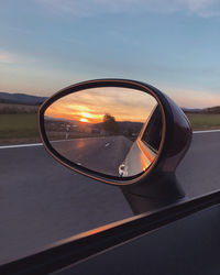 Close-up of sunglasses on side-view mirror against sunset sky