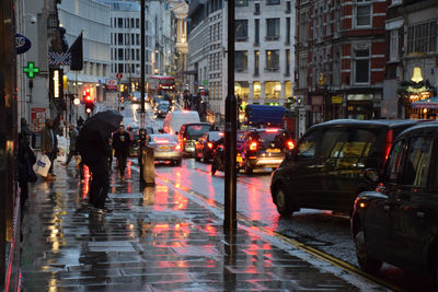 People on wet sidewalk during rainy season in city