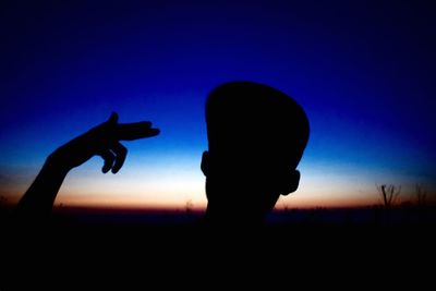 Silhouette of boy against sky during sunset