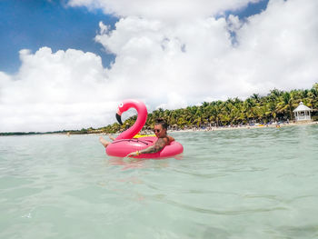 Young woman relaxing on pool raft in sea during vacation